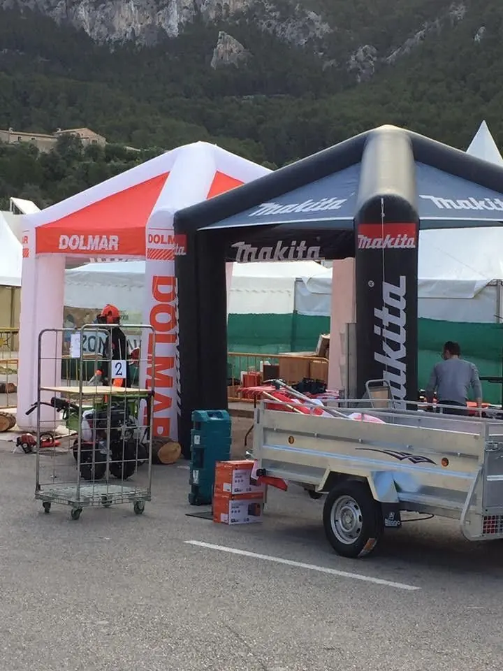 Arco hinchable negro de Makita junto a una carpa roja de Dolmar en una zona de feria