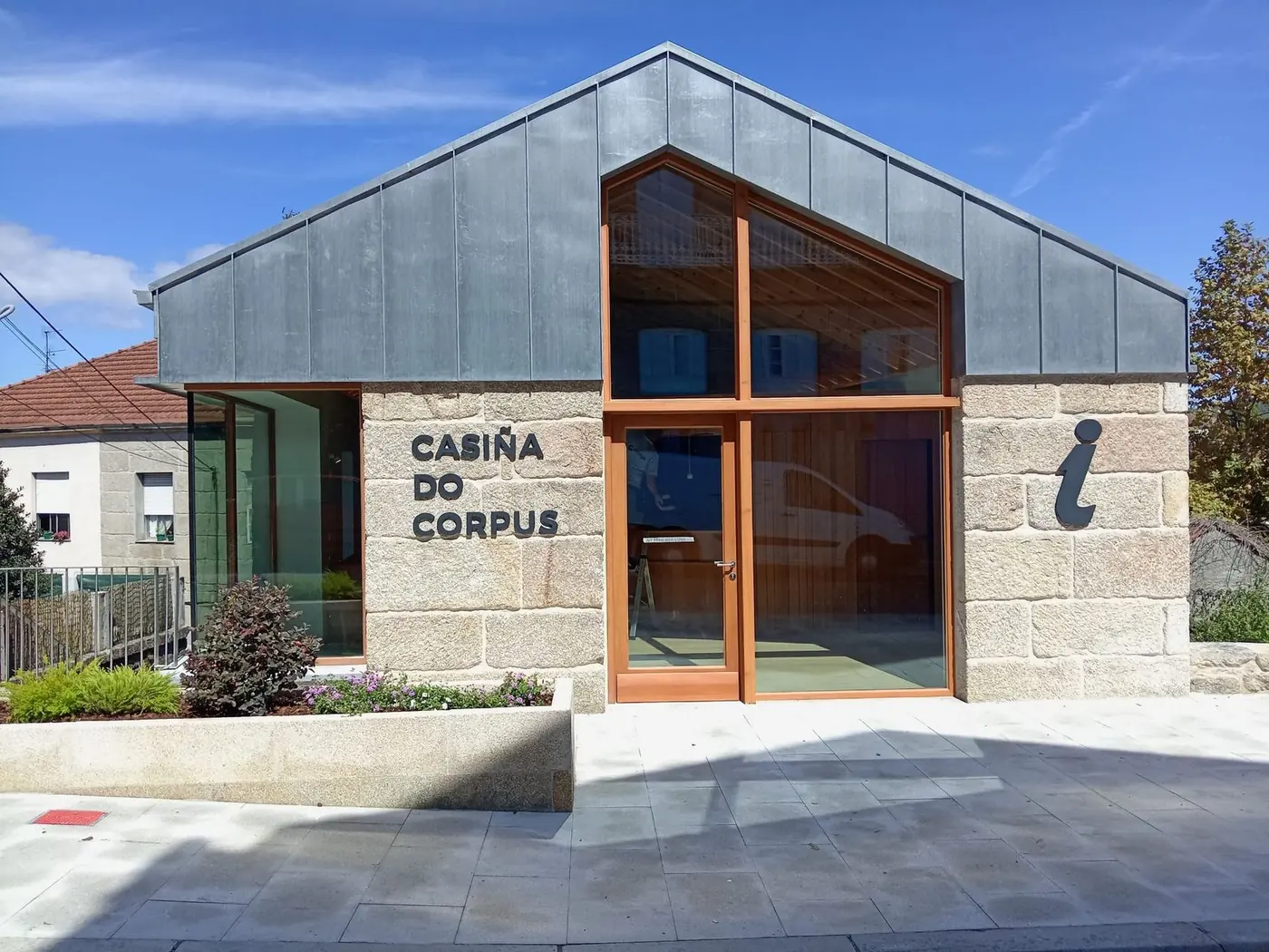 Fachada de piedra de la Casiña do Corpus con el nombre y el símbolo de información