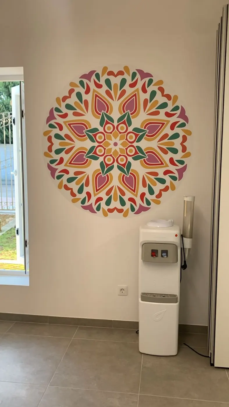 Mandala de colores en vinilo sobre una pared blanca junto a una ventana