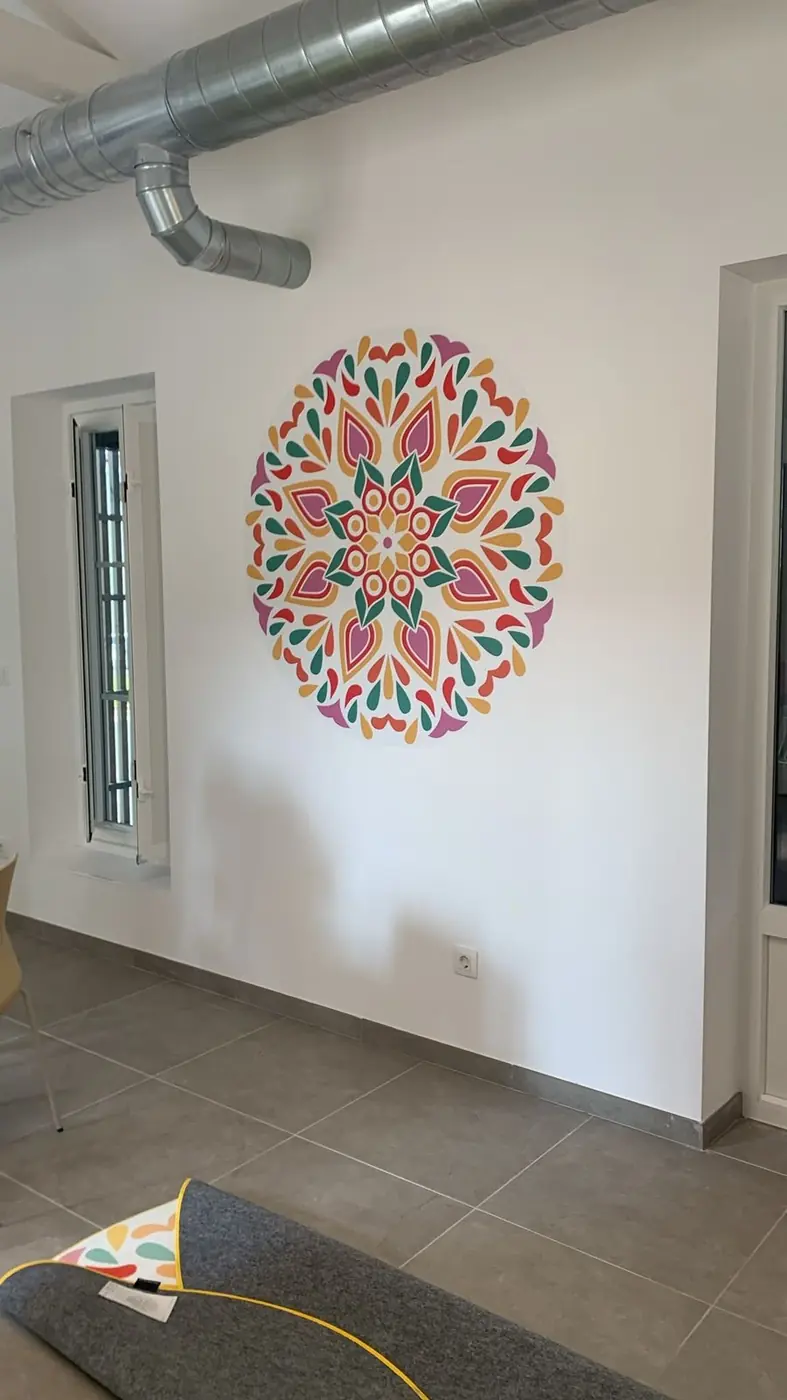 Mandala de colores en vinilo sobre la pared de una sala con instalación en curso