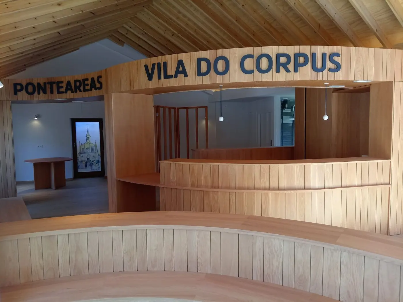 Mostrador de madera con el rótulo Vila do Corpus, Ponteareas, sobre la pared del interior
