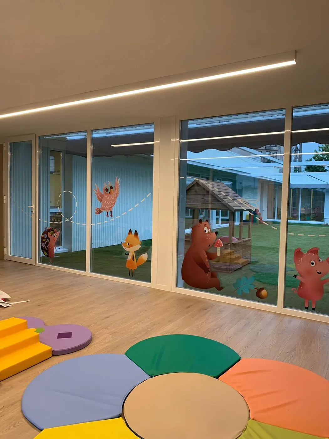 Aula con vinilos de animales en los cristales y alfombra de colores