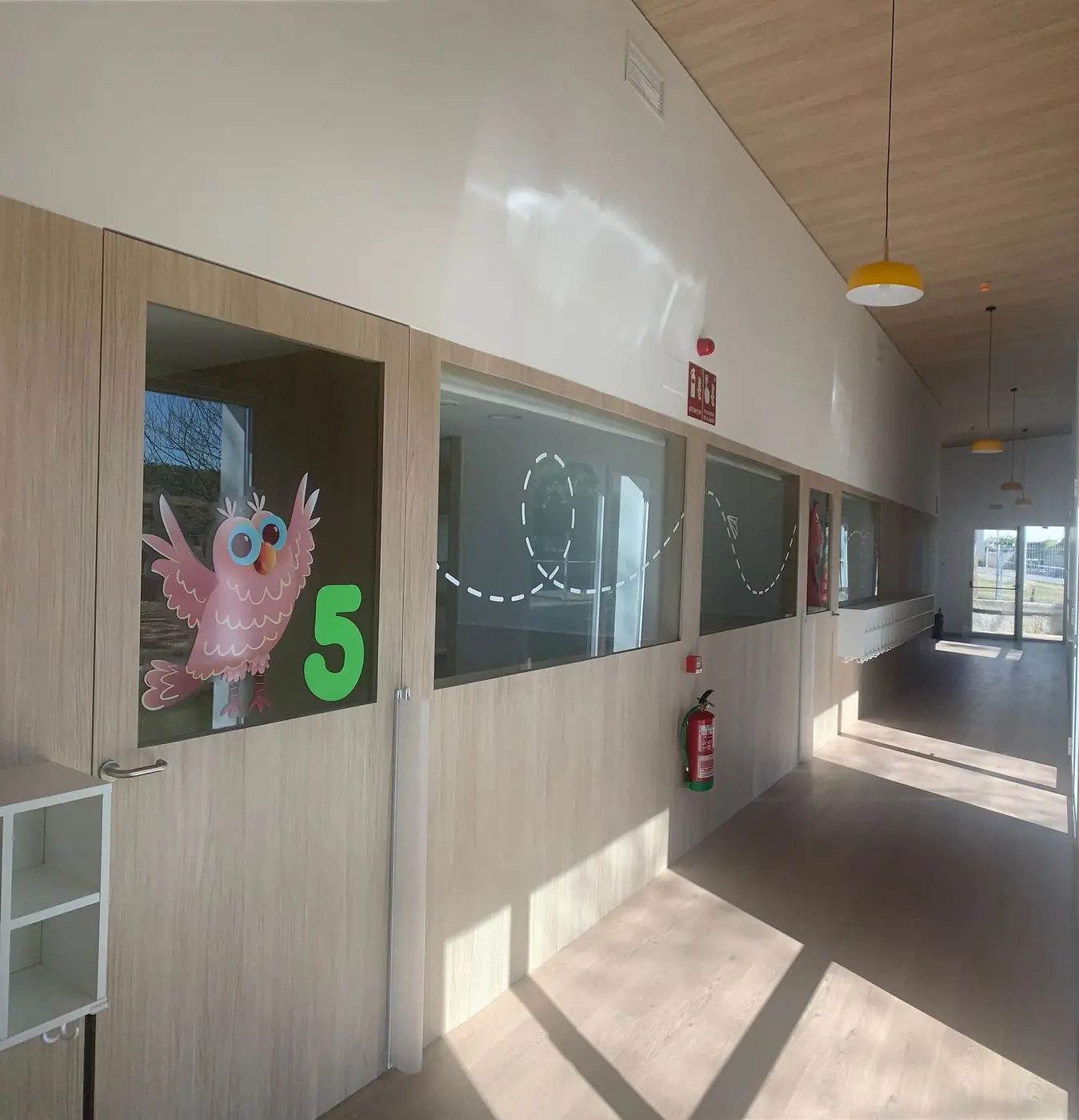 Vinilo de una lechuza rosa con el número 5 en la ventana de un aula