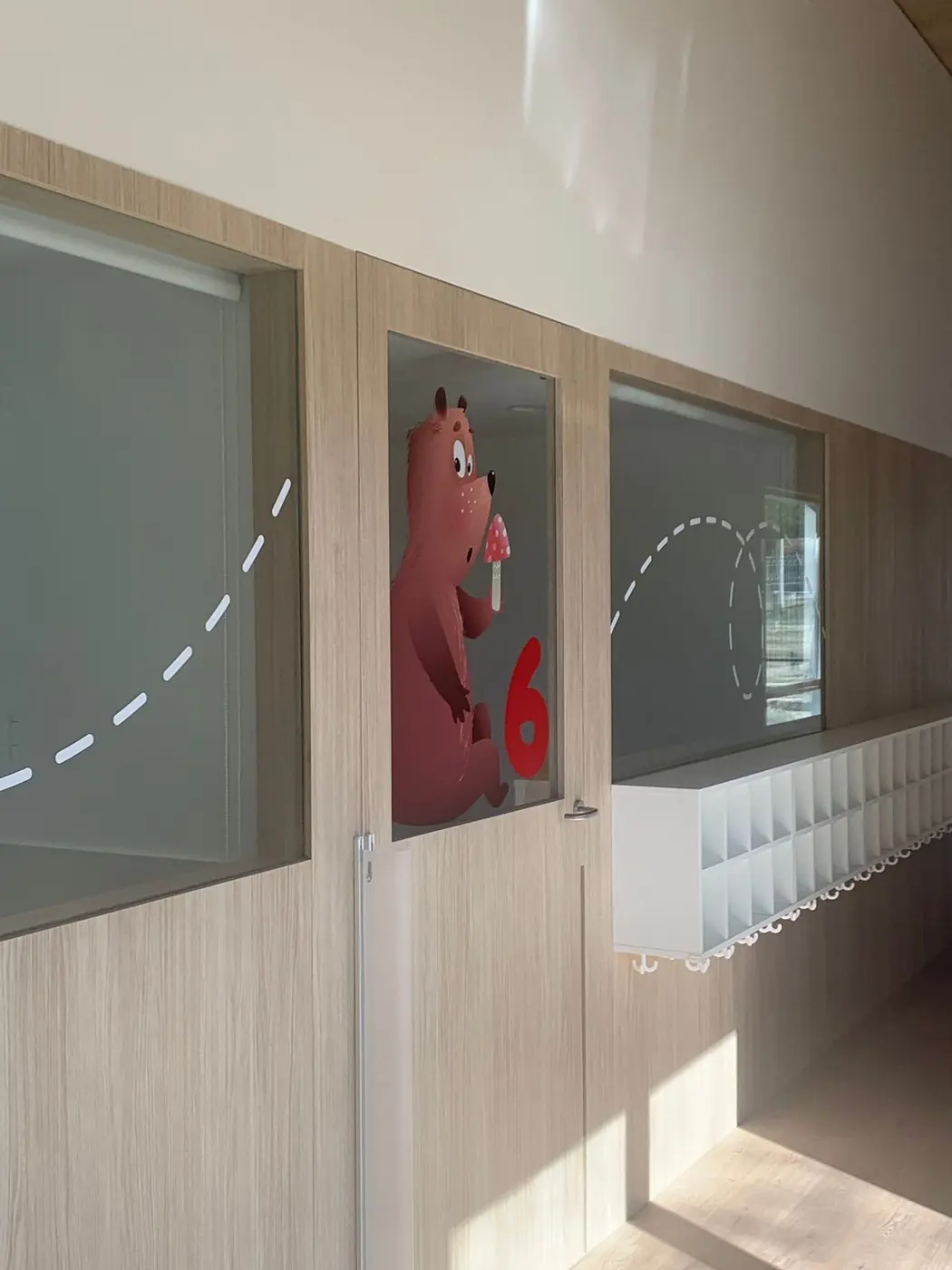 Pasillo con los vinilos de los animales numerados sobre las ventanas de las aulas