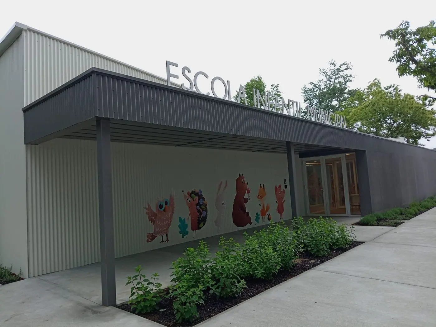 Entrada de la escuela infantil con el rótulo sobre la marquesina oscura
