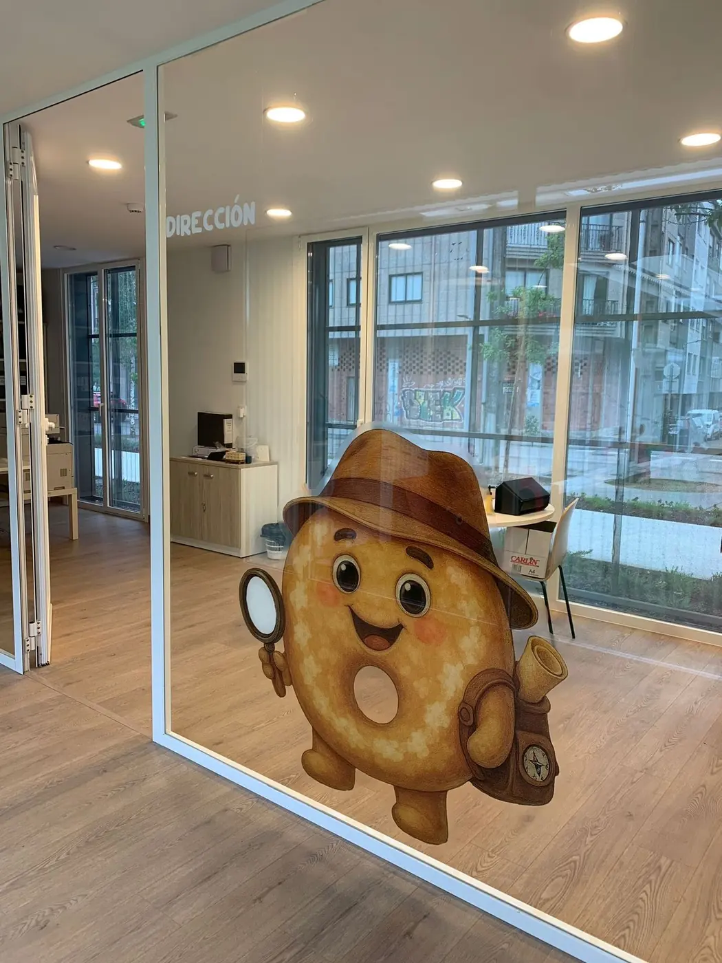 Mascota de la escuela, un personaje con sombrero, en vinilo sobre el cristal de una cristalera