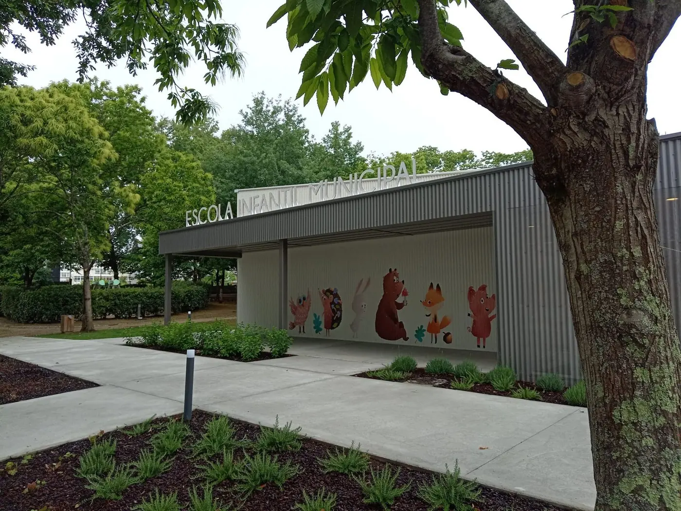 Entrada de la escuela infantil con un mural de animales del bosque sobre la pared bajo la marquesina