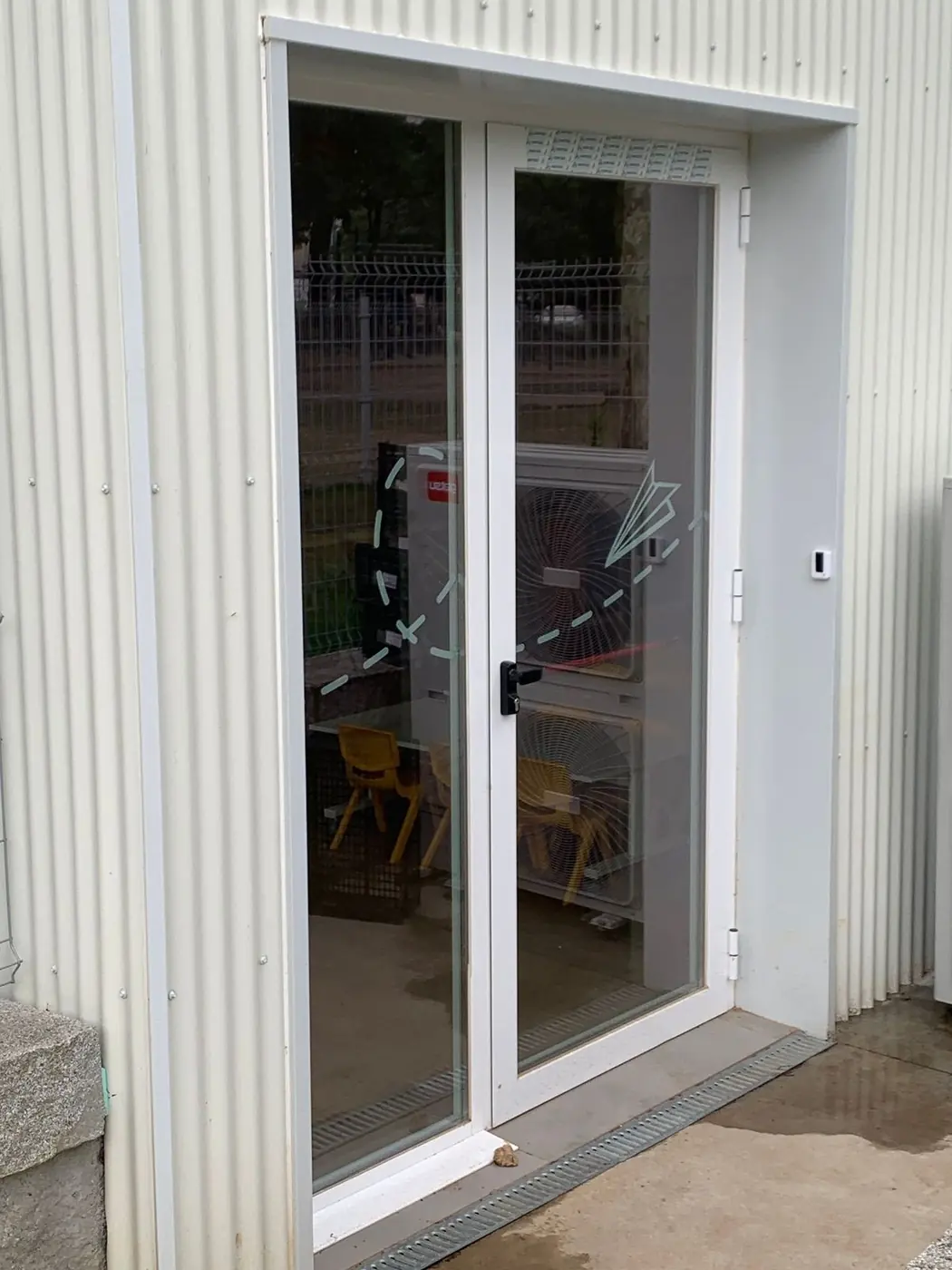 Puerta acristalada de la entrada con vinilos y señalización en el cristal