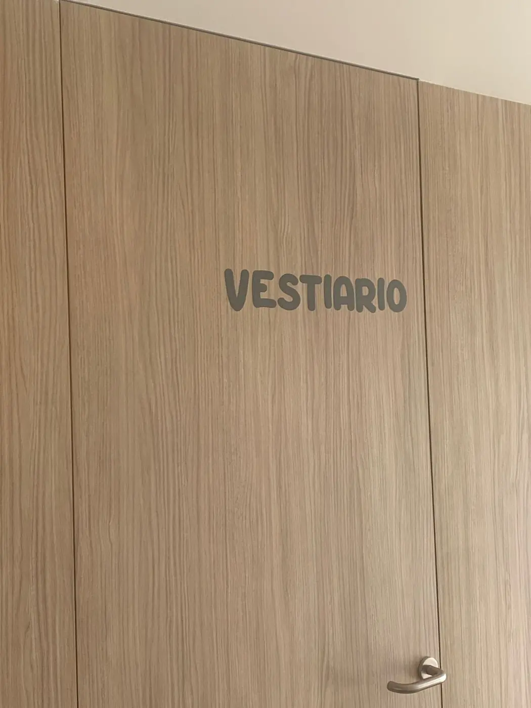 Rótulo Vestiario en gris sobre una puerta de madera