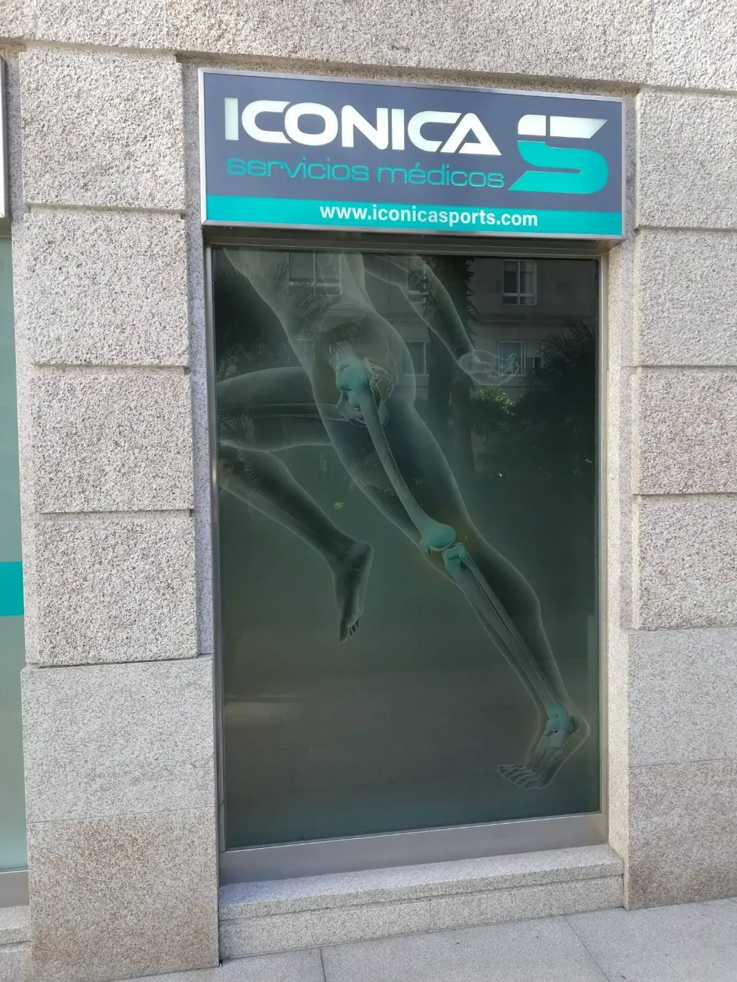 Rótulo luminoso de Iconica servicios médicos sobre un escaparate con una imagen anatómica de un corredor