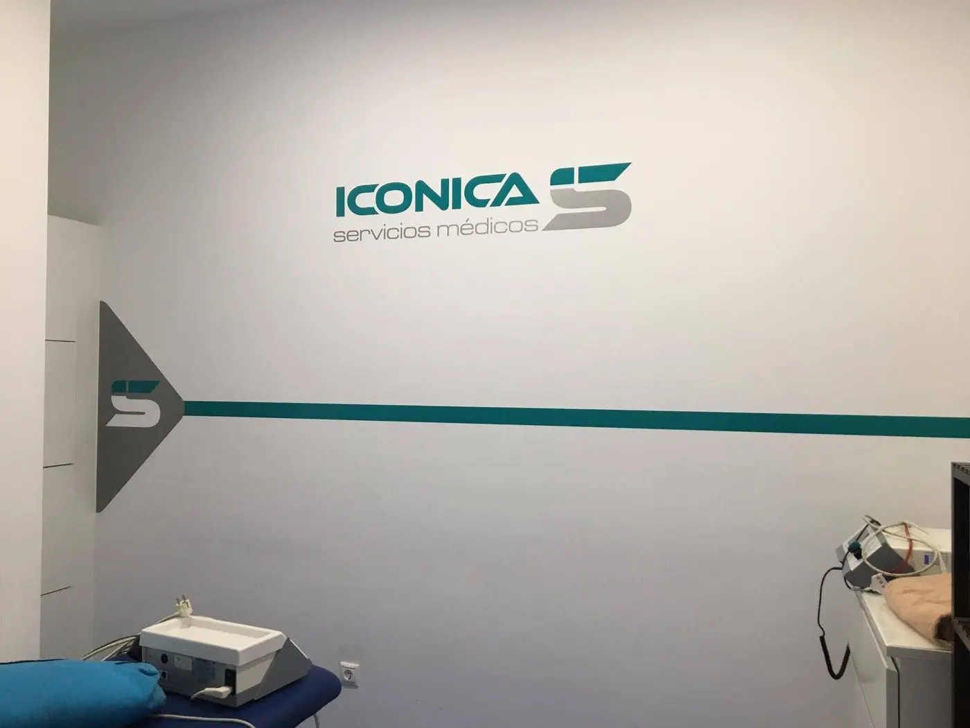 Pared interior de una consulta con el logotipo de Iconica, una franja turquesa y una flecha señalizadora