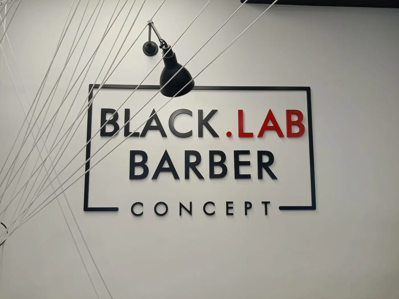 Rótulo de Black.Lab Barber Concept con marco y letras corpóreas sobre pared blanca