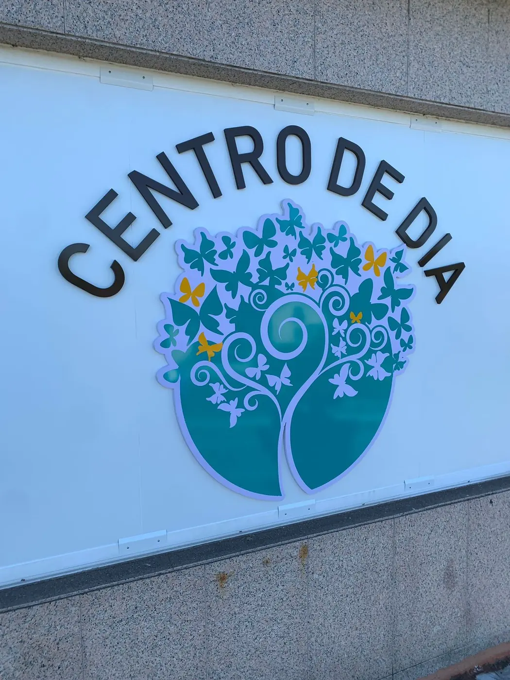 Rótulo Centro de Día con árbol en vinilo sobre pared de piedra