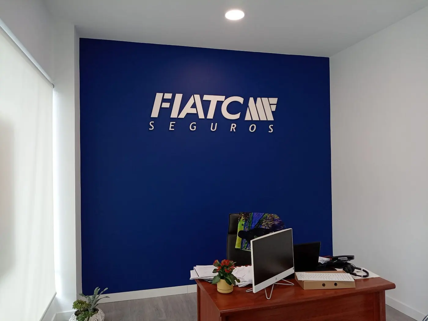 Letras corpóreas blancas de Fiatc Seguros sobre pared azul en una oficina
