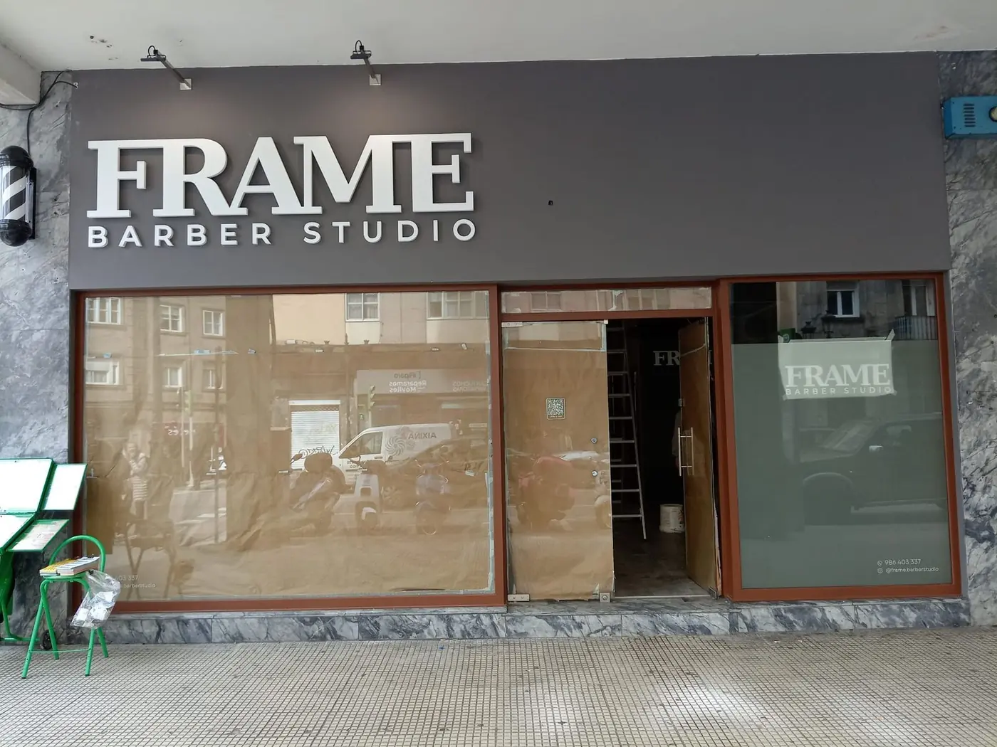 Fachada completa de Frame Barber Studio con las letras corpóreas sobre el rótulo gris