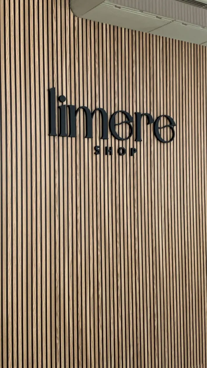 Letras negras de Limere Shop sobre un panel de lamas de madera
