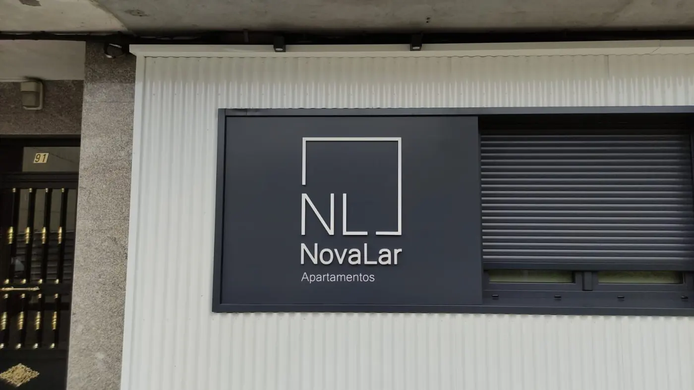 Rótulo de NovaLar Apartamentos sobre panel gris en un portal