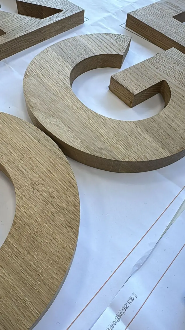 Letras de madera aún sin instalar sobre la mesa del taller