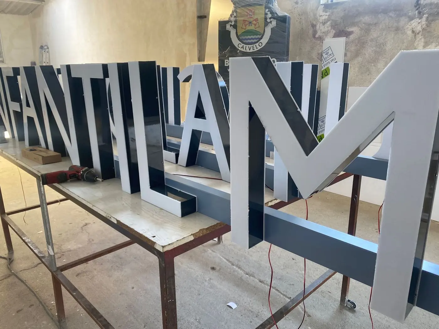 Estructura de letras corpóreas metálicas con cableado en la mesa del taller