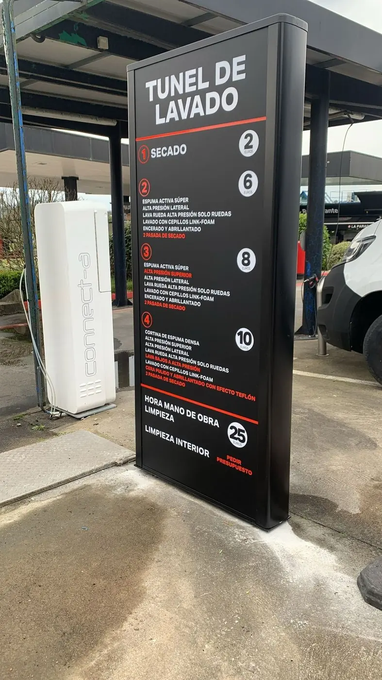 Tótem informativo de un túnel de lavado con instrucciones numeradas, junto a la pista de lavado