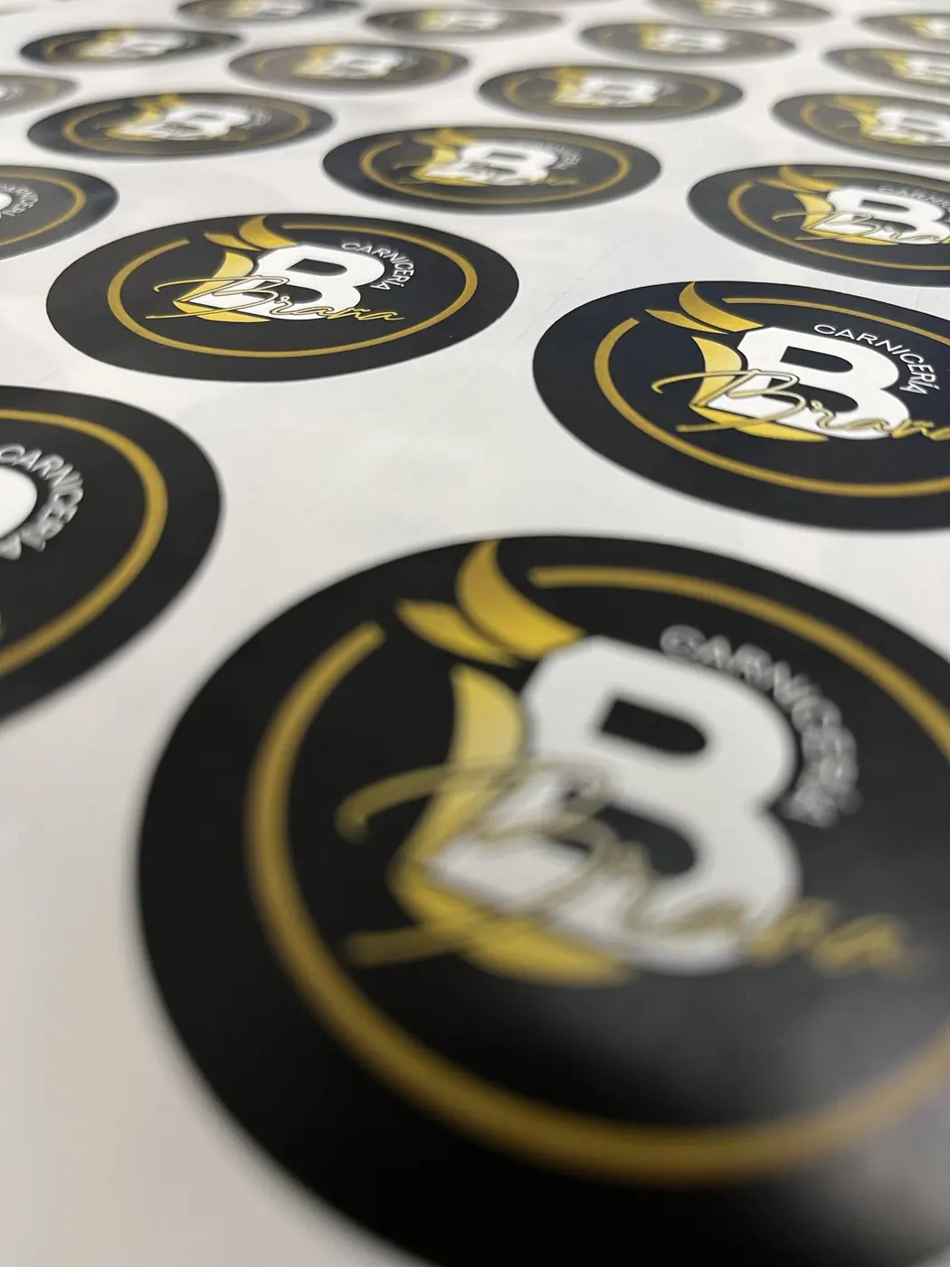 Pliego de pegatinas redondas con el logotipo de Carnicería B en negro y dorado