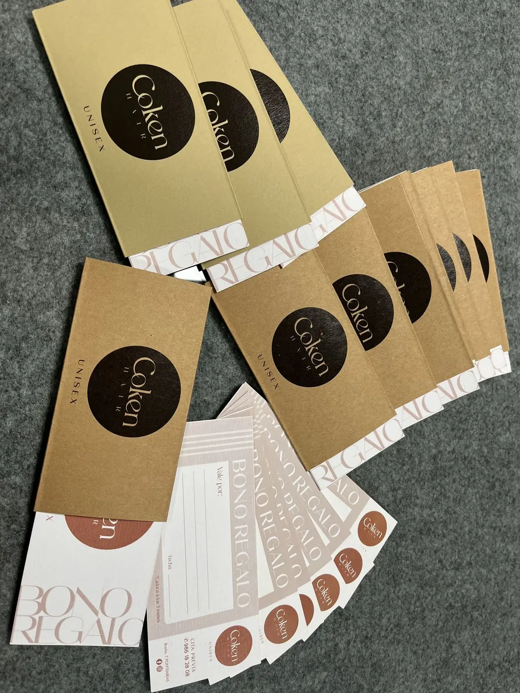 Sobres de cartón kraft con pegatina negra de Coken, tarjetas y bonos regalo repartidos sobre una mesa