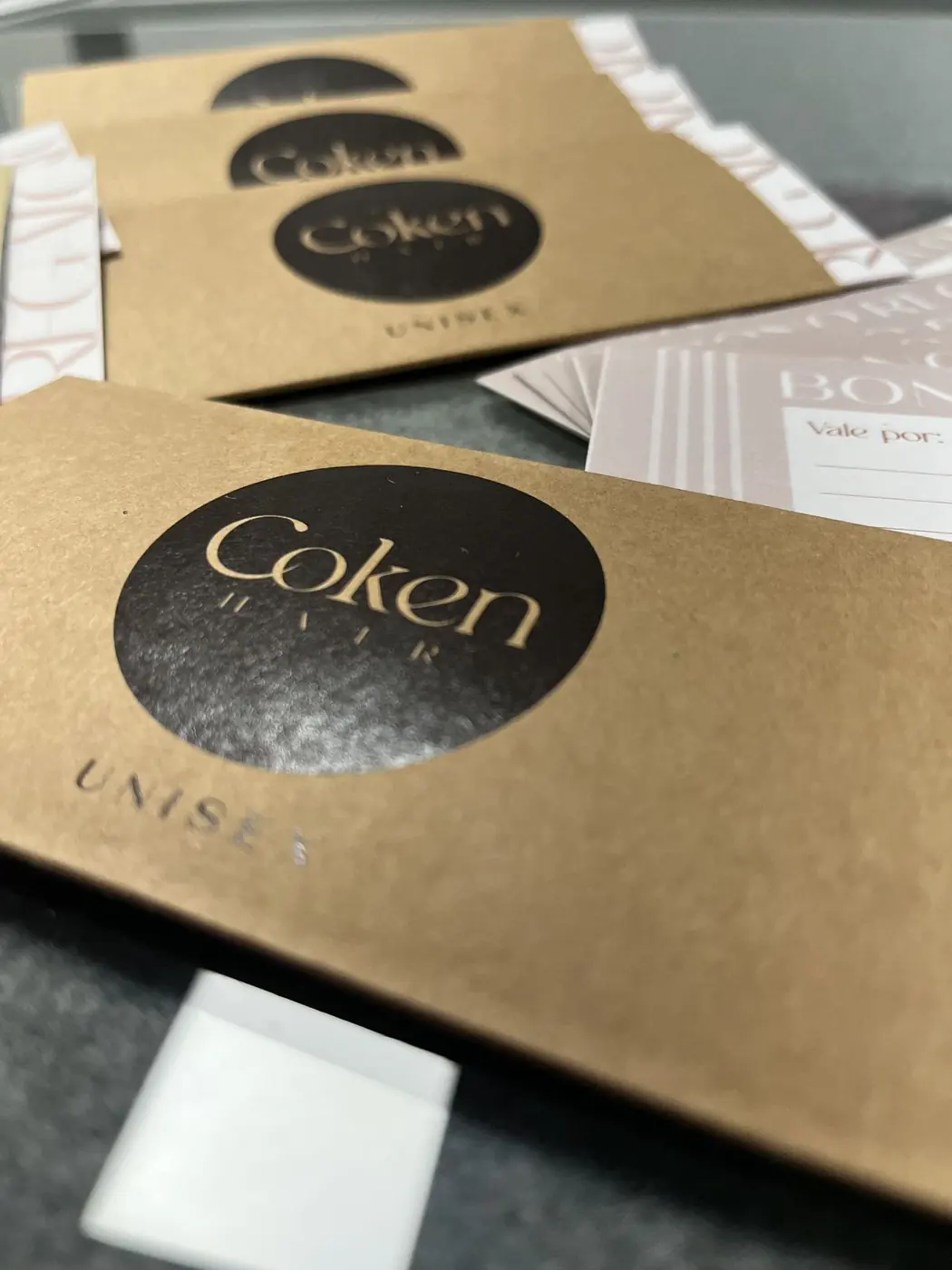 Detalle de un sobre kraft con pegatina circular de Coken sobre papel impreso