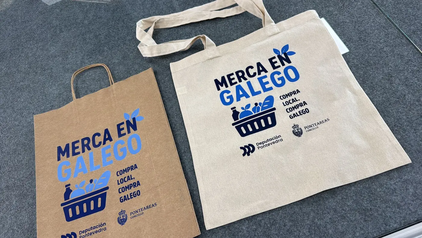Bolsa de papel kraft y bolsa de tela con el lema Merca en Galego, compra local, compra galego
