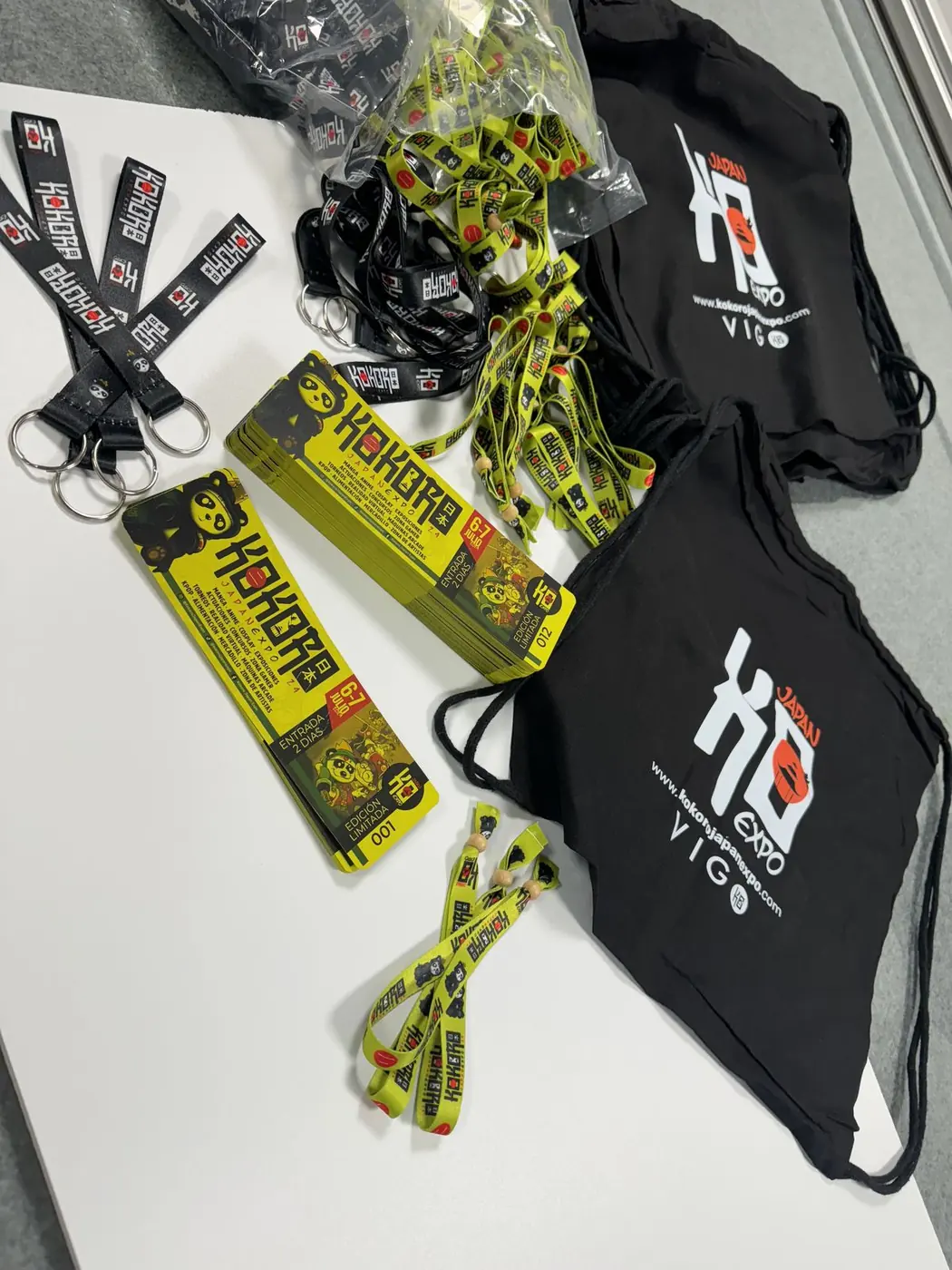Mochilas negras, lanyards y llaveros de tela de Kokoro Expo sobre una mesa