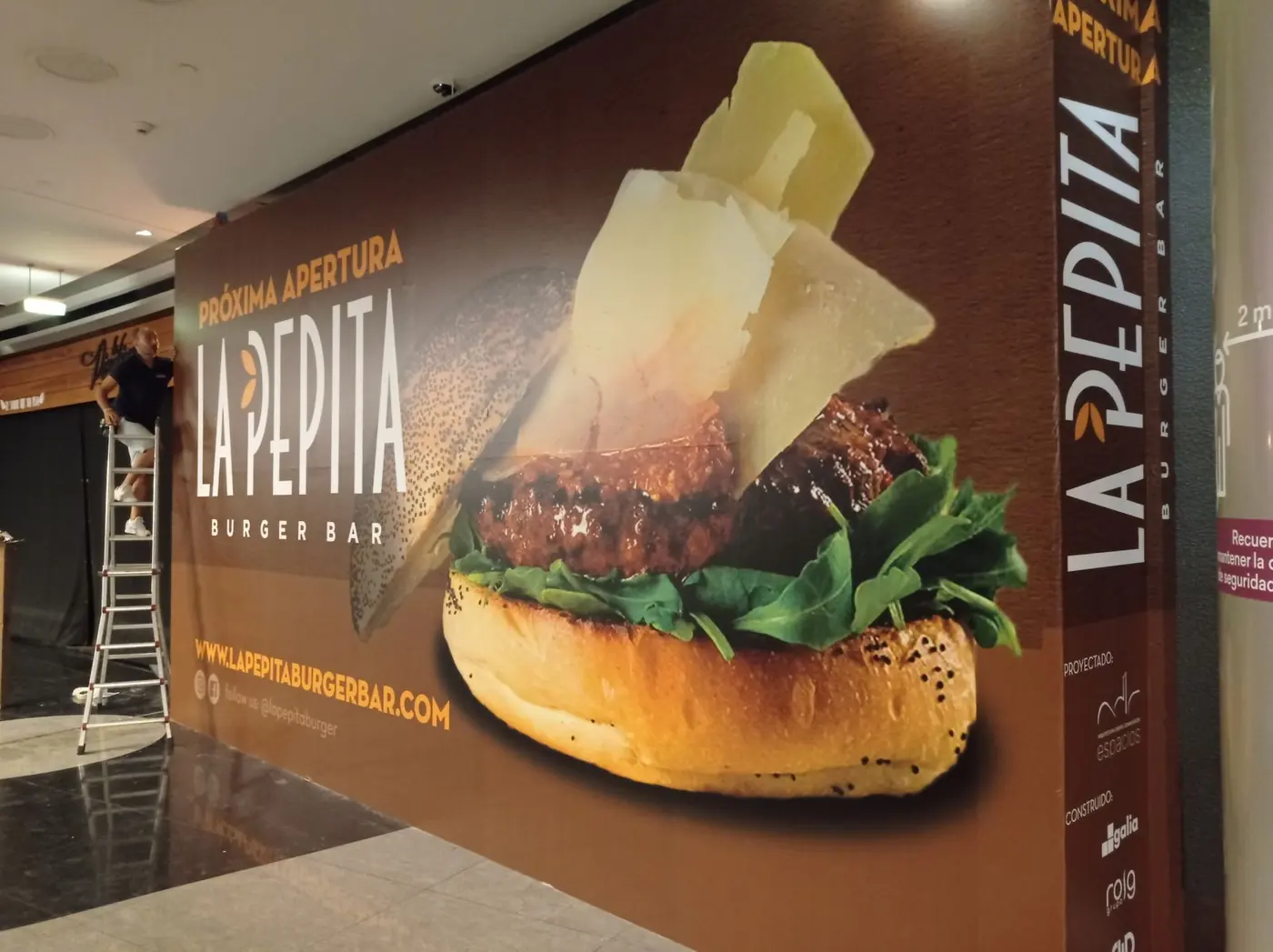 Lona de gran formato de La Pepita Burger Bar con la imagen de una hamburguesa, durante la instalación