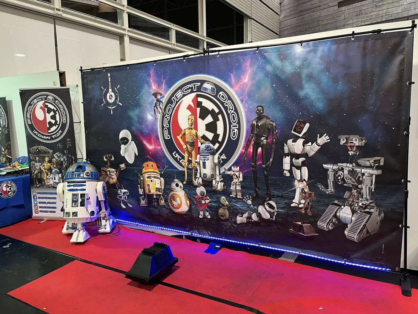 Photocall de lona impresa con robots y personajes de ciencia ficción sobre una alfombra roja
