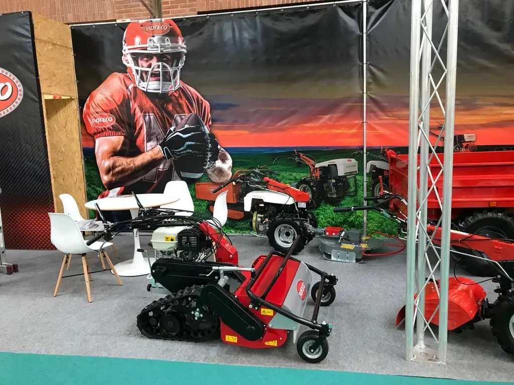 Stand de Roteco con una lona gigante de un jugador de fútbol americano y maquinaria expuesta