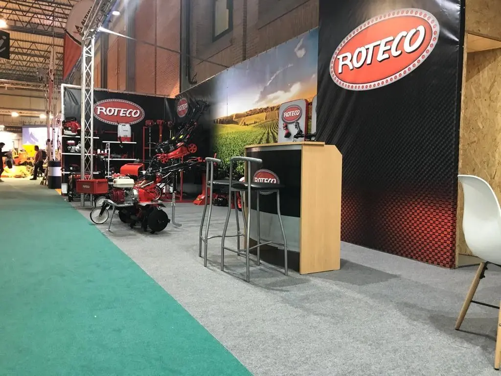 Pasillo del stand de Roteco con el fondo de lona impresa y el mostrador de madera