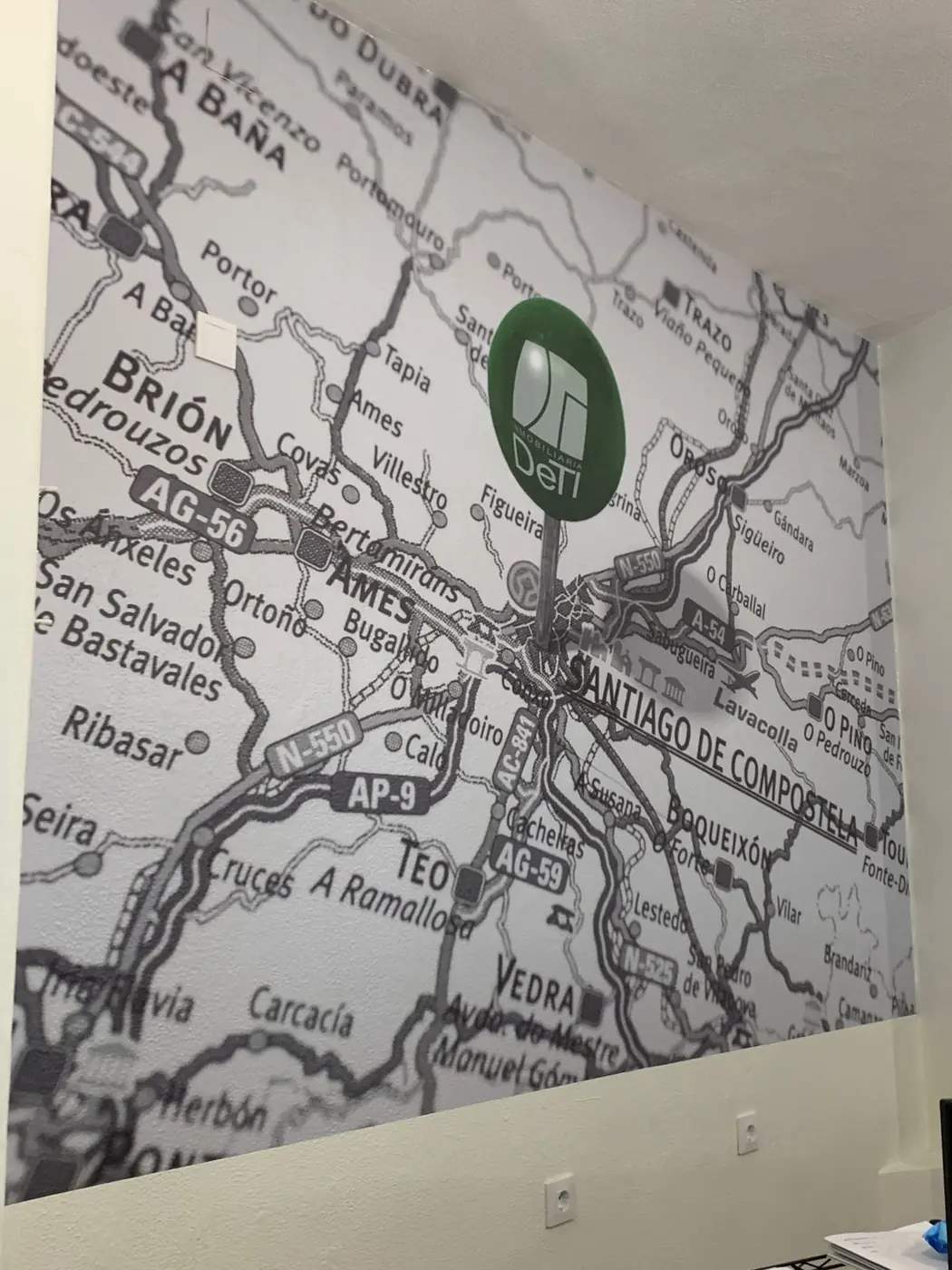 Vinilo de un mapa de carreteras en blanco y negro cubriendo una pared completa, con un logotipo verde